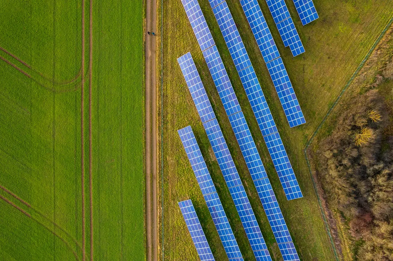 Aerial view of solar panels in a rural field surrounded by green farmland